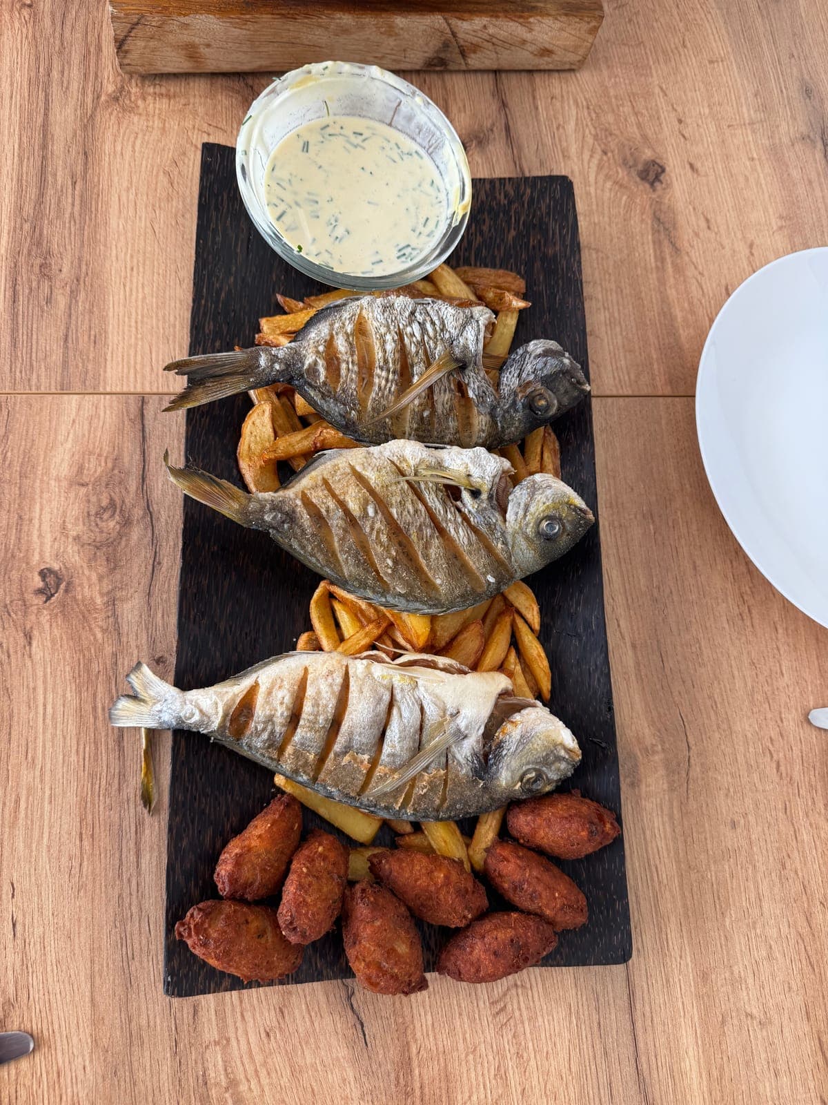 Trois daurades frites avec des frites sur une planche, vues du dessus